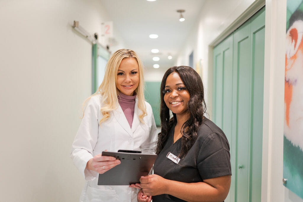 Dr. Wright and dental team member standing in hallway smiling at camera