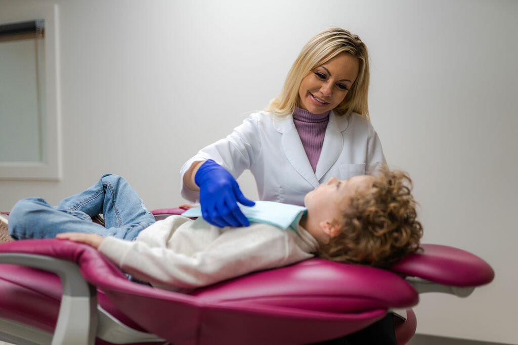 Dentist smiling at young patient in dental chair