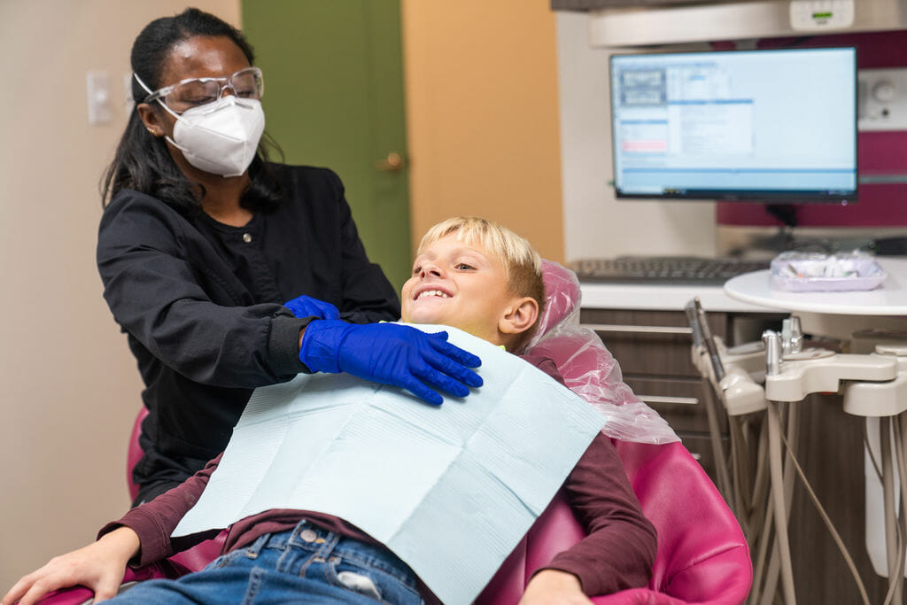 Dental hygienist preparing child for dental exam